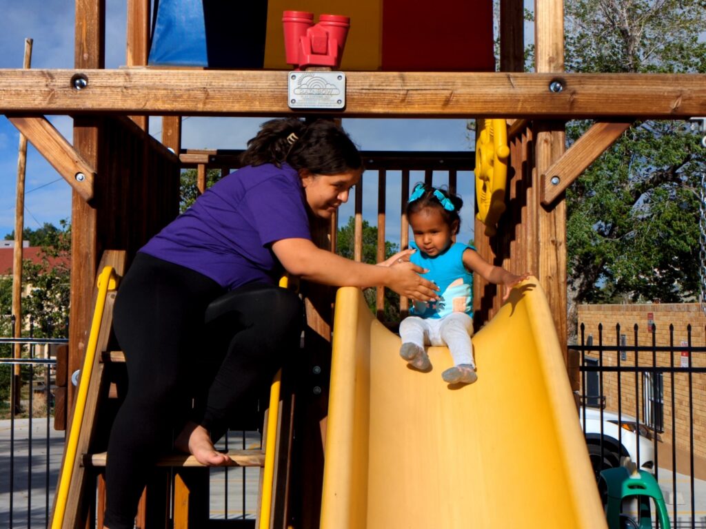 Yaney helping her daughter down the slide